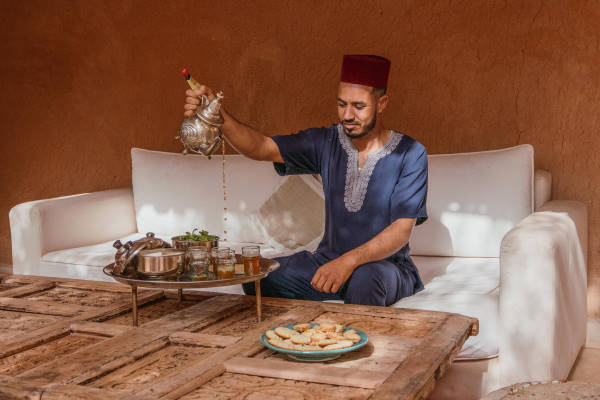 Homme en tenue traditionnel marocaine bleue servant le thé à la menthe