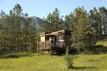 Cabane Andromède entouré de sapin avec une femme sur la terrasse