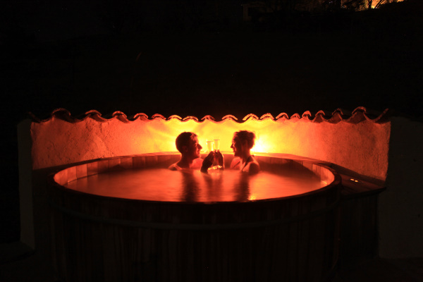 Couple de nuit dans le bain nordique éclairé avec des coupes de champagne