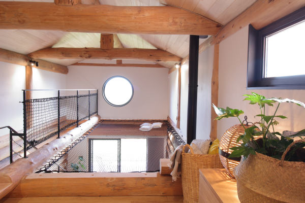 logement insolite lot - Photo de la mezzanine très lumineuse avec un filet de bateau tendu au dessus la pièce principale et au bout un occulus
