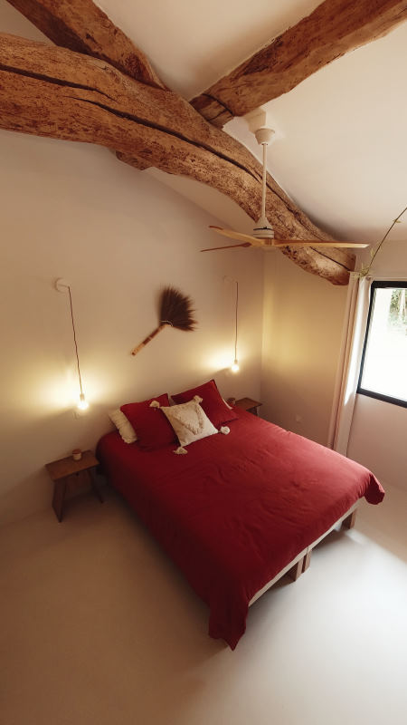 écolodge occitanie - Chambre minimaliste avec une poutre en bois brut apparente et dans les tons rouges