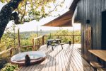 Terrasse d'une cabane avec un spa privé avec une femme de dos et une voile pour apporter de l'ombre