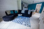 Photo of the dining room with a dark blue sofa, turquoise and light blue cousins, behind a repainted wooden buffet and a turquoise wall