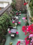 Garden Hotel. Photo du pation prise depuis une des chambres. Patio très fleuri et avec du mobilier dans les ton rose et vert