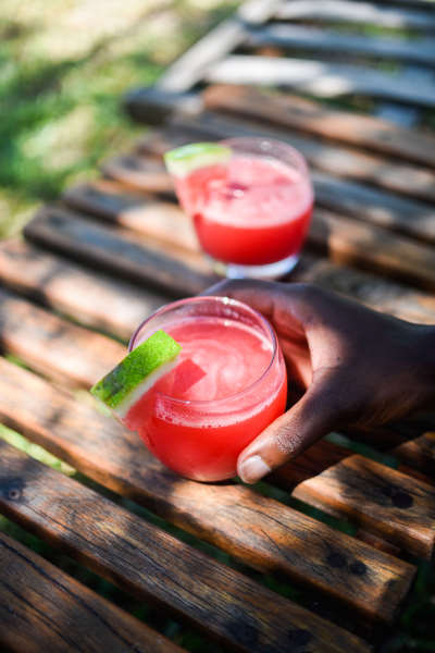 2 verres de cocktails de couleur rosé avec une tranche de citron posés sur une table en bois.