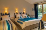 Photo de la chambre ton bleu avec un lit double, un lit simple et une baie vitrée avec accès direct au jardin