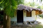 Minca - Reserva Caoba. Photo d'un des bungalow aux murs blanc et toit de paille entouré d'arbres