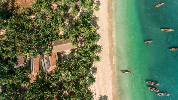 Lalay Lodge vue du ciel avec à droite la mer turquoise, au centre la plage de sable et à gauche les palmiers où se cachent les bâtiments de l'hotel