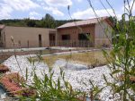 Photo prise dans le jardin au premier plan il y a la piscine et derrière la maison d'hôtes