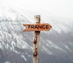 panneau en bois en forme de fleche dans un paysage montagneux enneige avec écrit France dessus