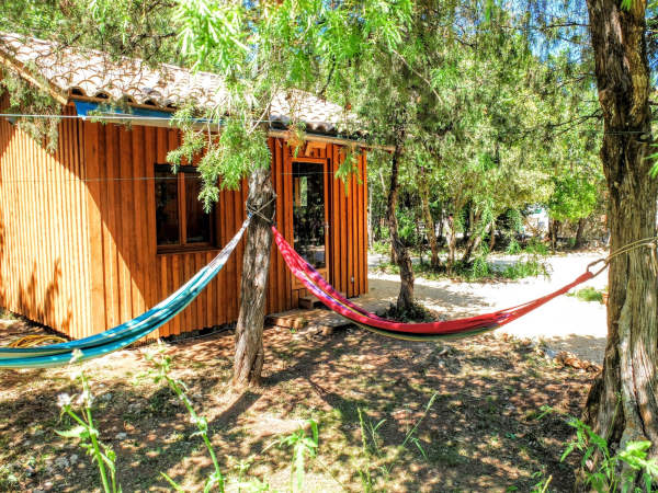 2 hamacs de couleurs accrochés à un arbre devant la cabane en bois