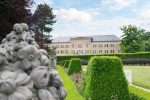 Bâtiment ocre avec son grand jardin et ses arbustes bien taillés