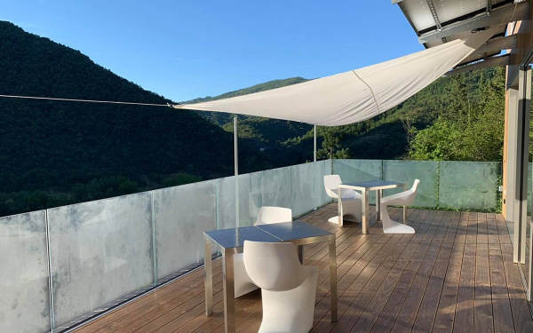 écolodge italie - terrasse avec mobilier blanc design et balustrade en verre et une vue dégagée sur les montagnes