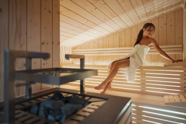 hotel spa dolomites - Femme dans un sauna vêtue d'une serviette éponge blanche