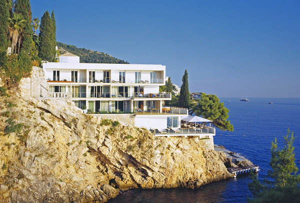 Hotel de murs blancs avec design moderne et épuré, construit le long de la roche avec accès direct à la mer