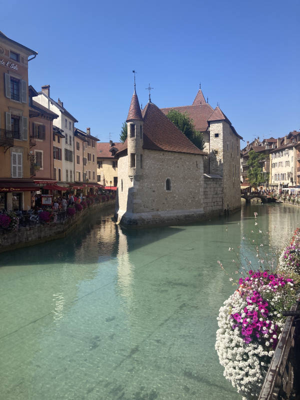 Old prison annecy with the canal with translucent water and flowered barriers