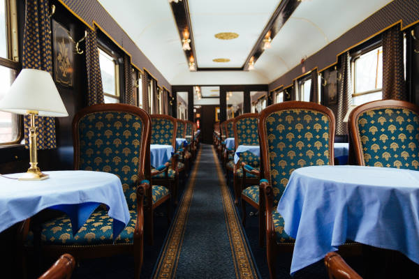 voyage en train mythique - intérieur wagon restaurant de l'orient express avec ses grands fauteuils vert et tables nappées