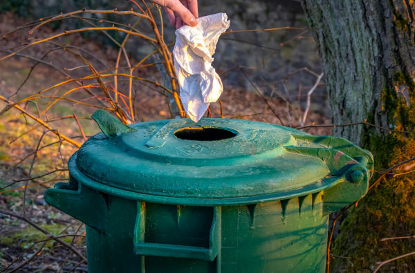 sport écologique - Main jetant un papier dans une poubelle verte