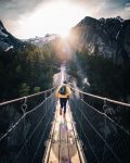 sport écologique - homme de dos avec un coupe vent jaune courant sur un pont de signe au dessus des arbres