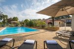 Photo prise de la terrasse de la piscine avec des transats noirs et des serviettes dessus, des parasols autour de la piscine rectangle