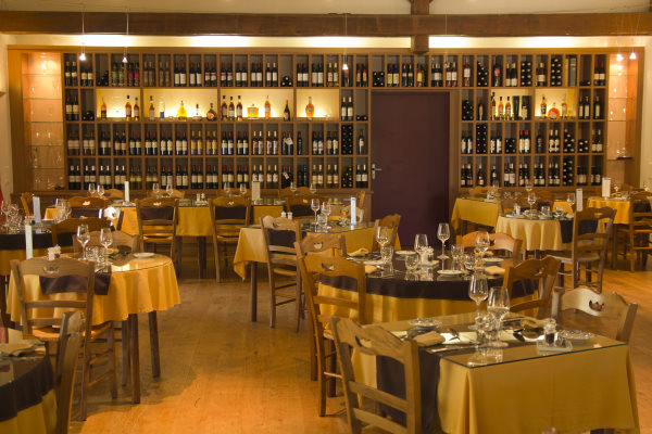 hôtel de charme gers - intérieur du restaurant avec tablés dressées et au fond une cave à vin