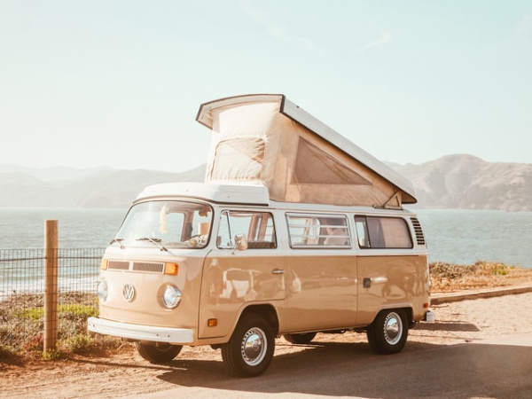 White and beige Volkswagen Combi with folded roof installed at the seaside