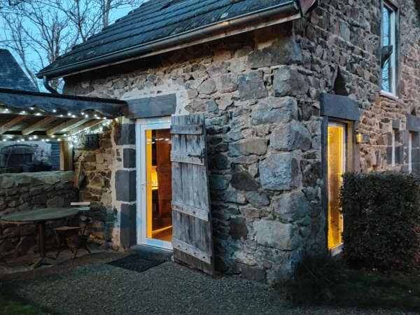 maison d’hôtes puy de dôme - poulailler en pierre renové pris en photo à la tombée de l anuit avec de la lumière derrière les fenêtres