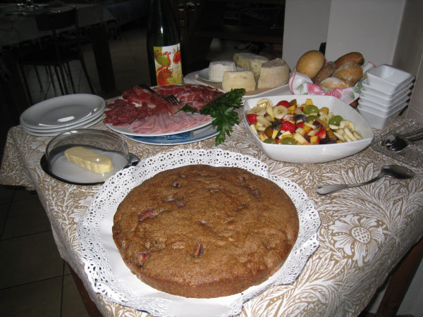 table garnies avec plusieurs plats pour le repas : tarte maison, charcuterie locale, fromages locaux